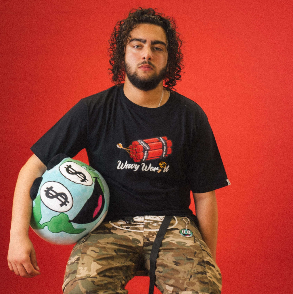Person wearing the black Wavy World DA Bomb Tee from Drop 1 - Hip Hop & Cereal, styled with casual streetwear, standing against a Red background.