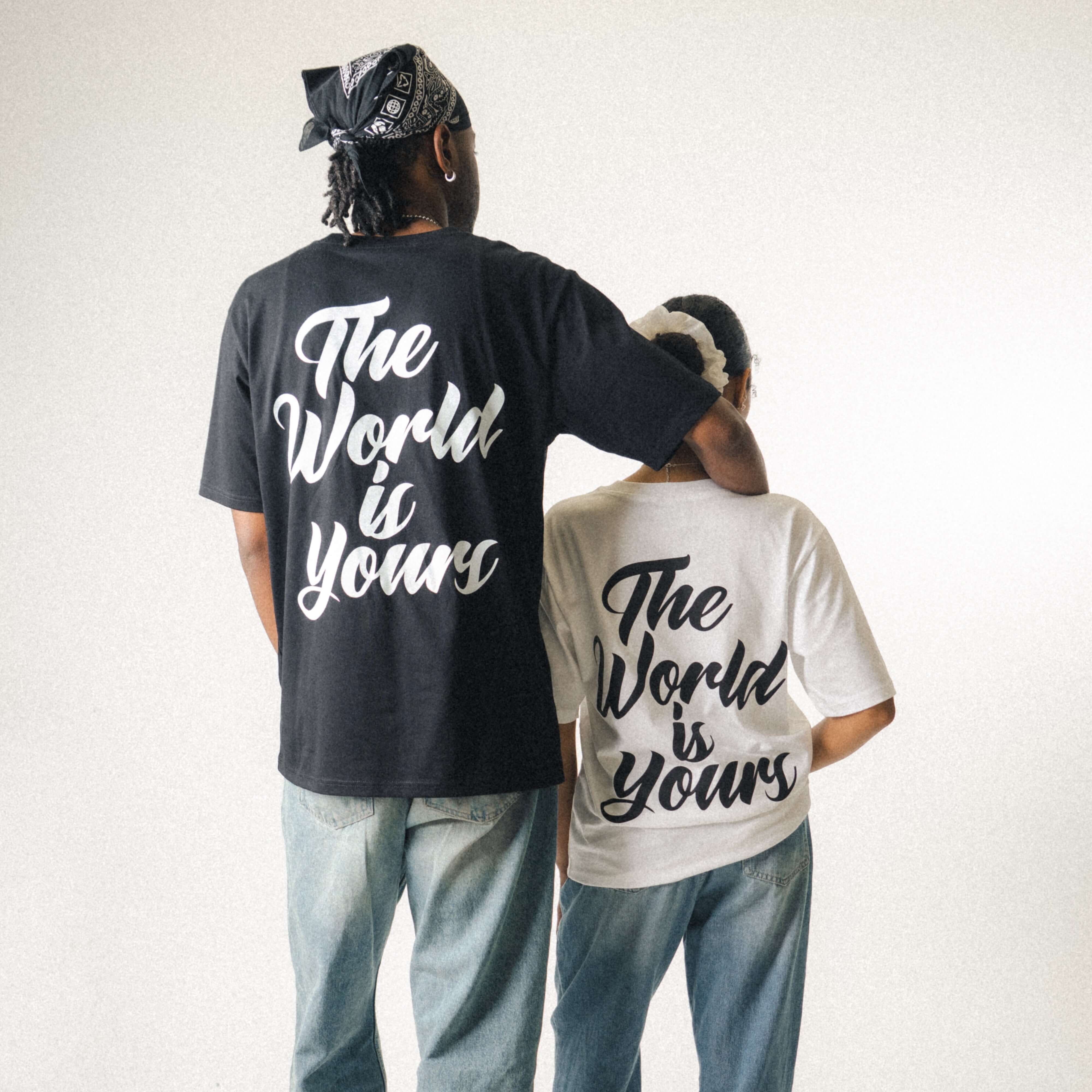 Two people standing together as a couple wearing Wavy World 'The World Is Yours' Tees in black and white from Drop 1 - Hip Hop & Cereal, styled.
