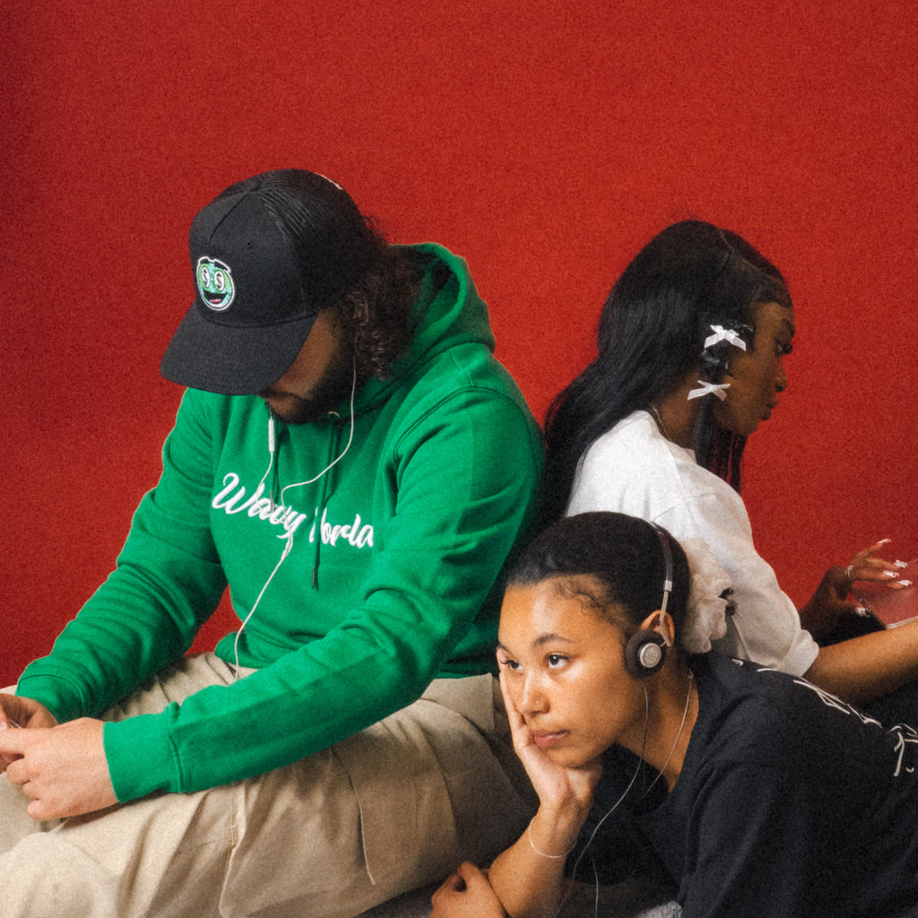 Person wearing the black Wavy World Trucker Cap from Drop 1 – Hip Hop & Cereal, styled with relaxed streetwear, standing against a vibrant red background, bringing throwback energy with a modern edge.